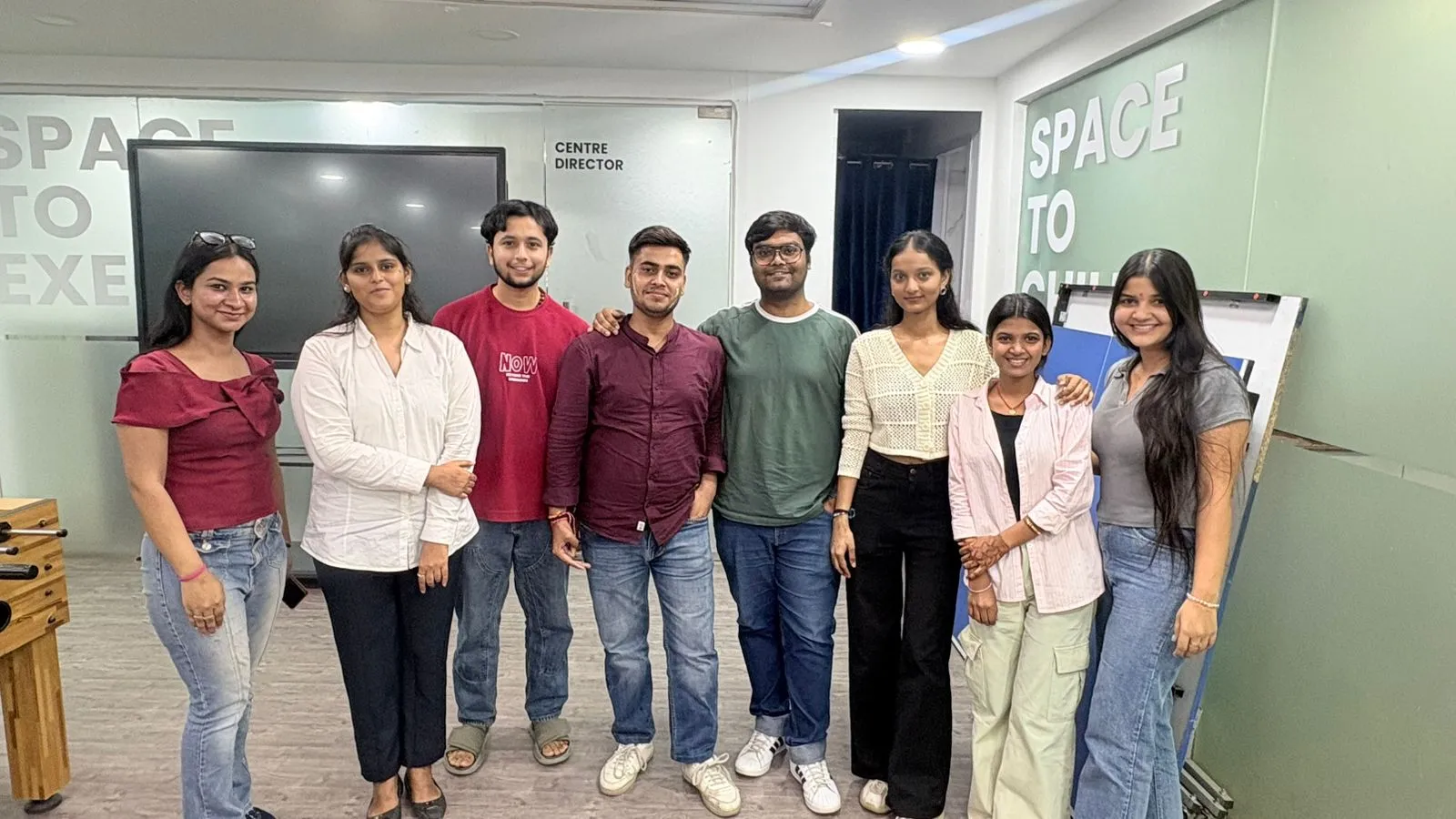 A whiteboard covered in Python snippets and browser tabs, five students gathered around a single screen in a Delhi office