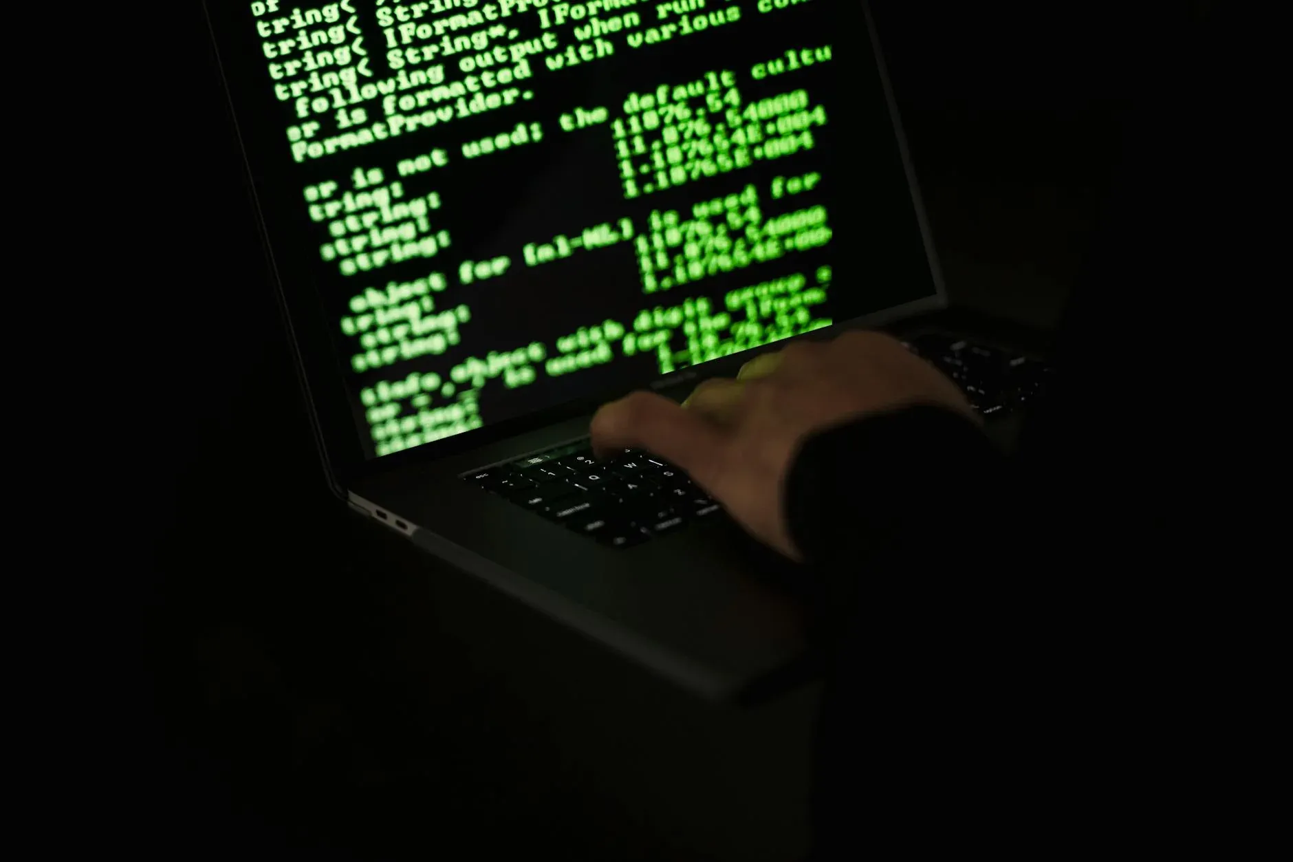 Hacker in dark room with multiple screens — cybersecurity and ransomware attack
